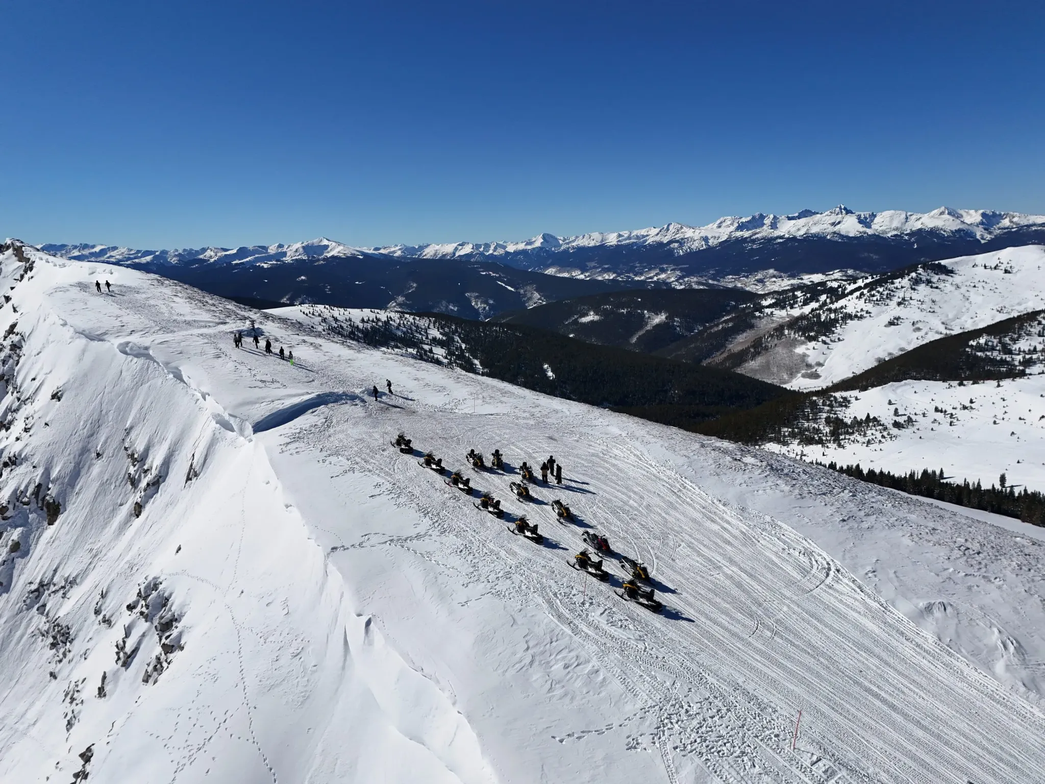 Snowmobile riders on a guided tour near Beaver Creek, Colorado with Rocky Mountain views.